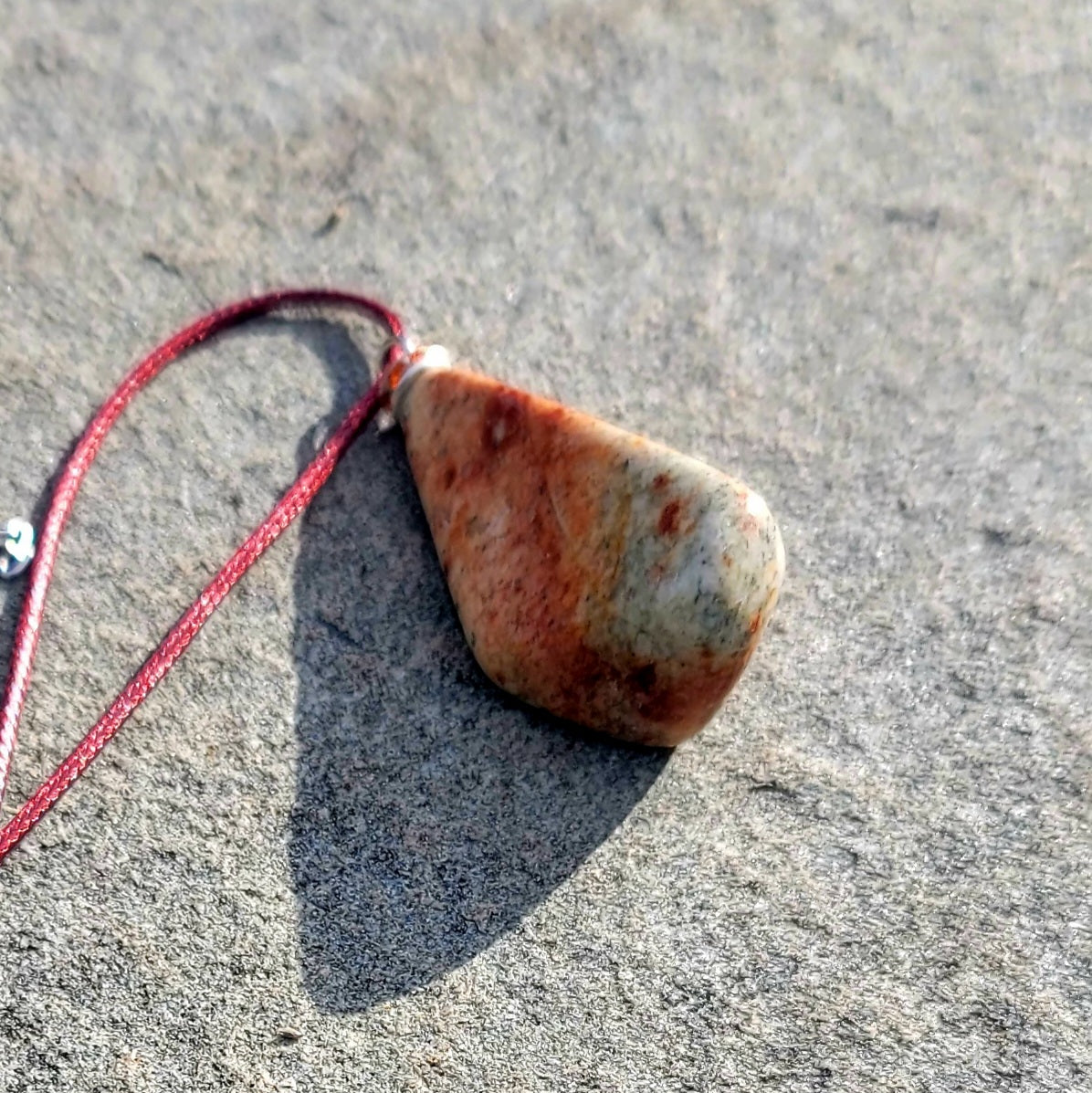 Very unique and powerful sunstone pendant. This stone has an intriguing color pattern consisting of Reds, Oranges, Green and Brown. It also has a unique shape that will definitely stand out. This is a true one-of-a-kind piece.