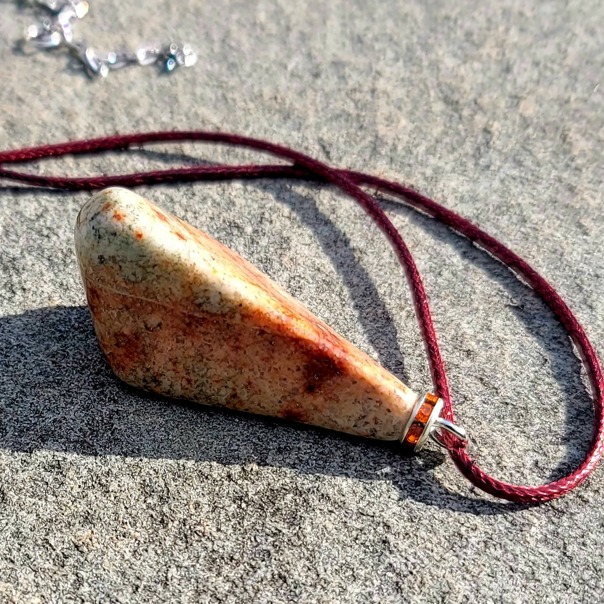 Very unique and powerful sunstone pendant. This stone has an intriguing color pattern consisting of Reds, Oranges, Green and Brown. It also has a unique shape that will definitely stand out. This is a true one-of-a-kind piece.