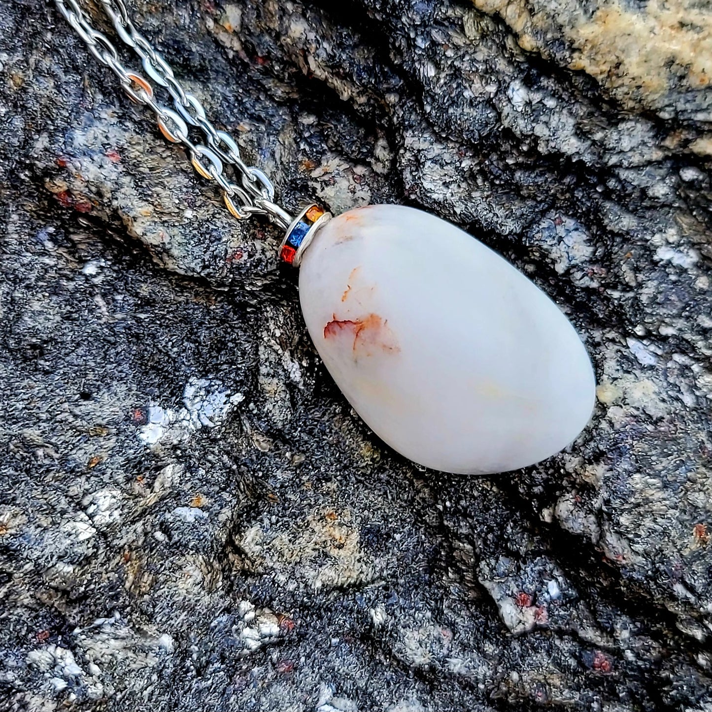 BEAUTIFUL WHITE QUARTZ GEMSTONE PENDANT WITH TRACES OF RED AND BLACK.