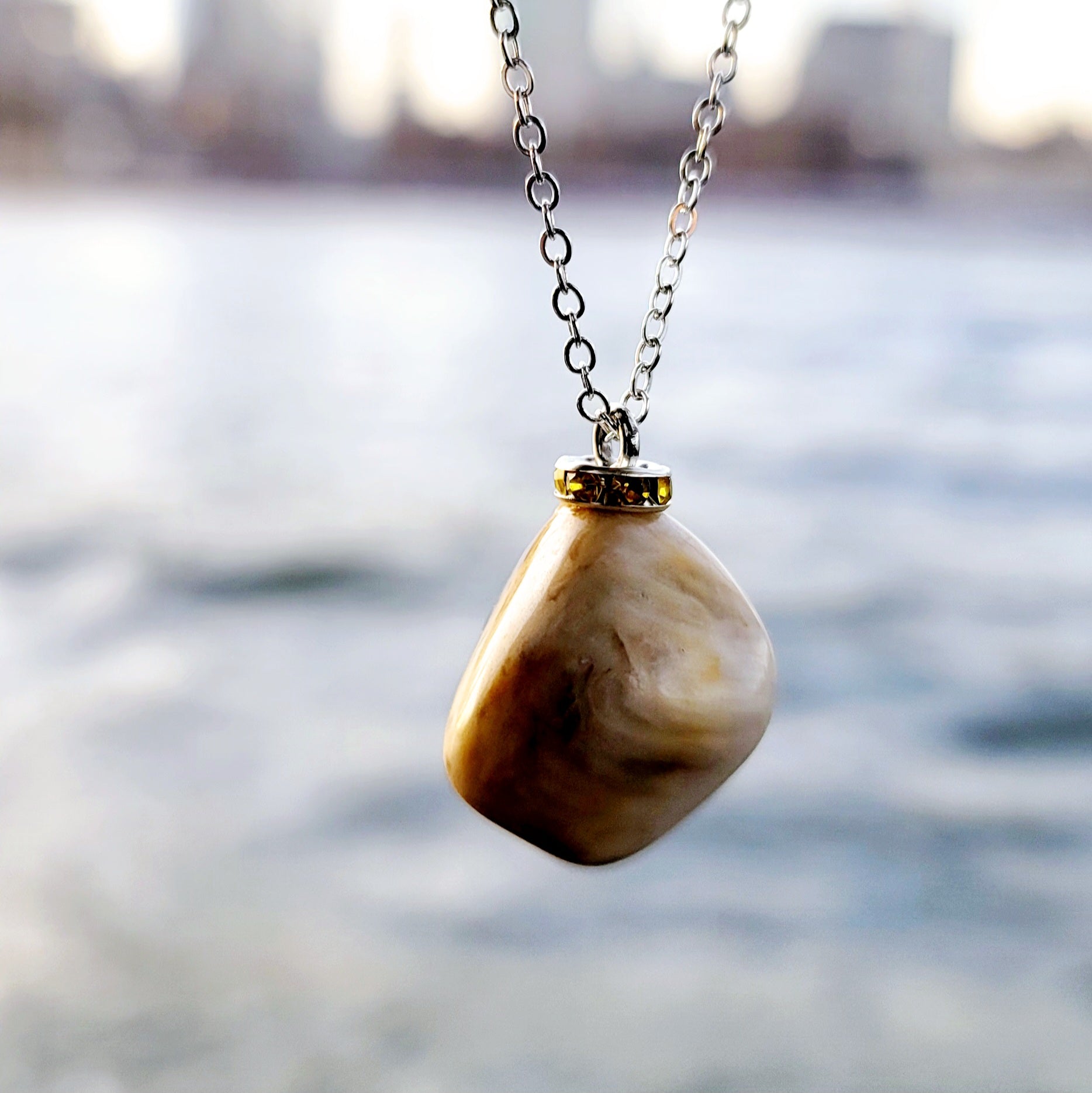 This intricately crafted zebra marble gemstone pendant is a one-of-a-kind masterpiece. Meticulously cut and polished to create an elegant pattern of black, yellow and white striped patterns. This pendant is trimmed with a stainless steel, 20" chain.