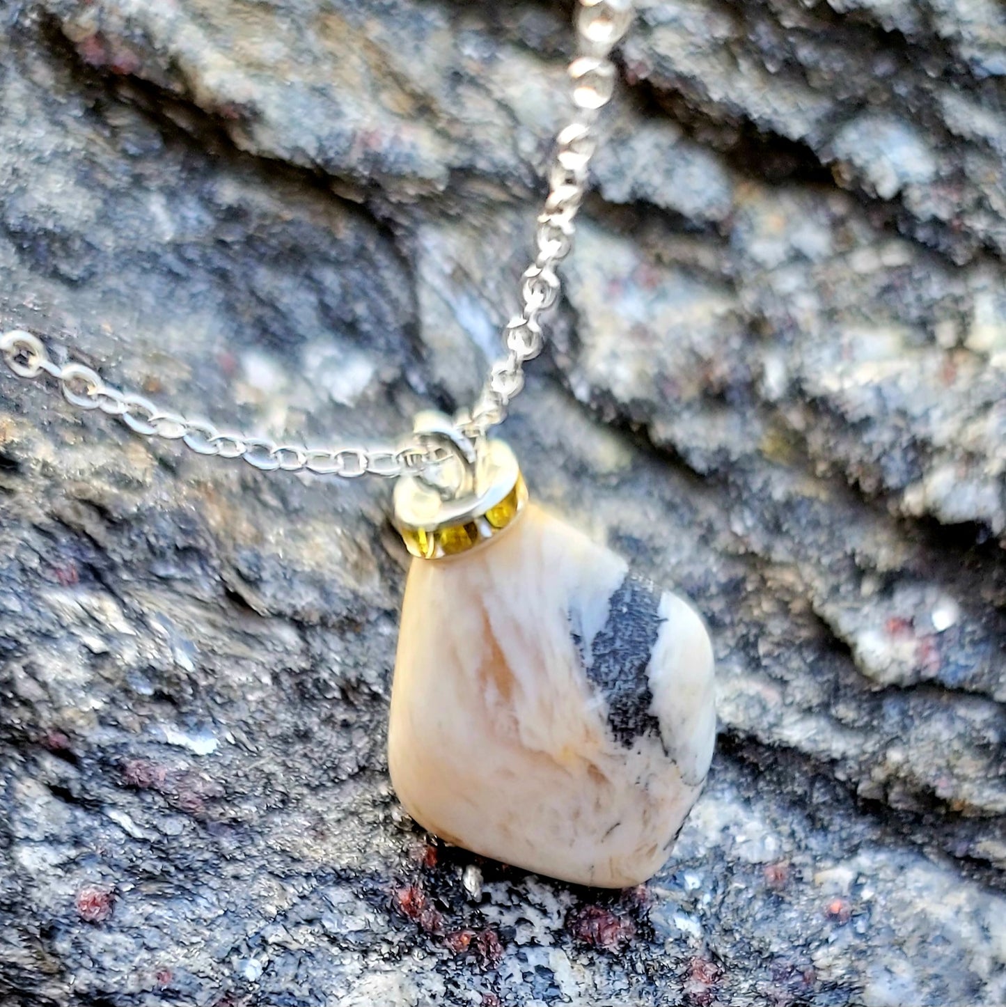 This intricately crafted zebra marble gemstone pendant is a one-of-a-kind masterpiece. Meticulously cut and polished to create an elegant pattern of black, yellow and white striped patterns. This pendant is trimmed with a stainless steel, 20" chain.