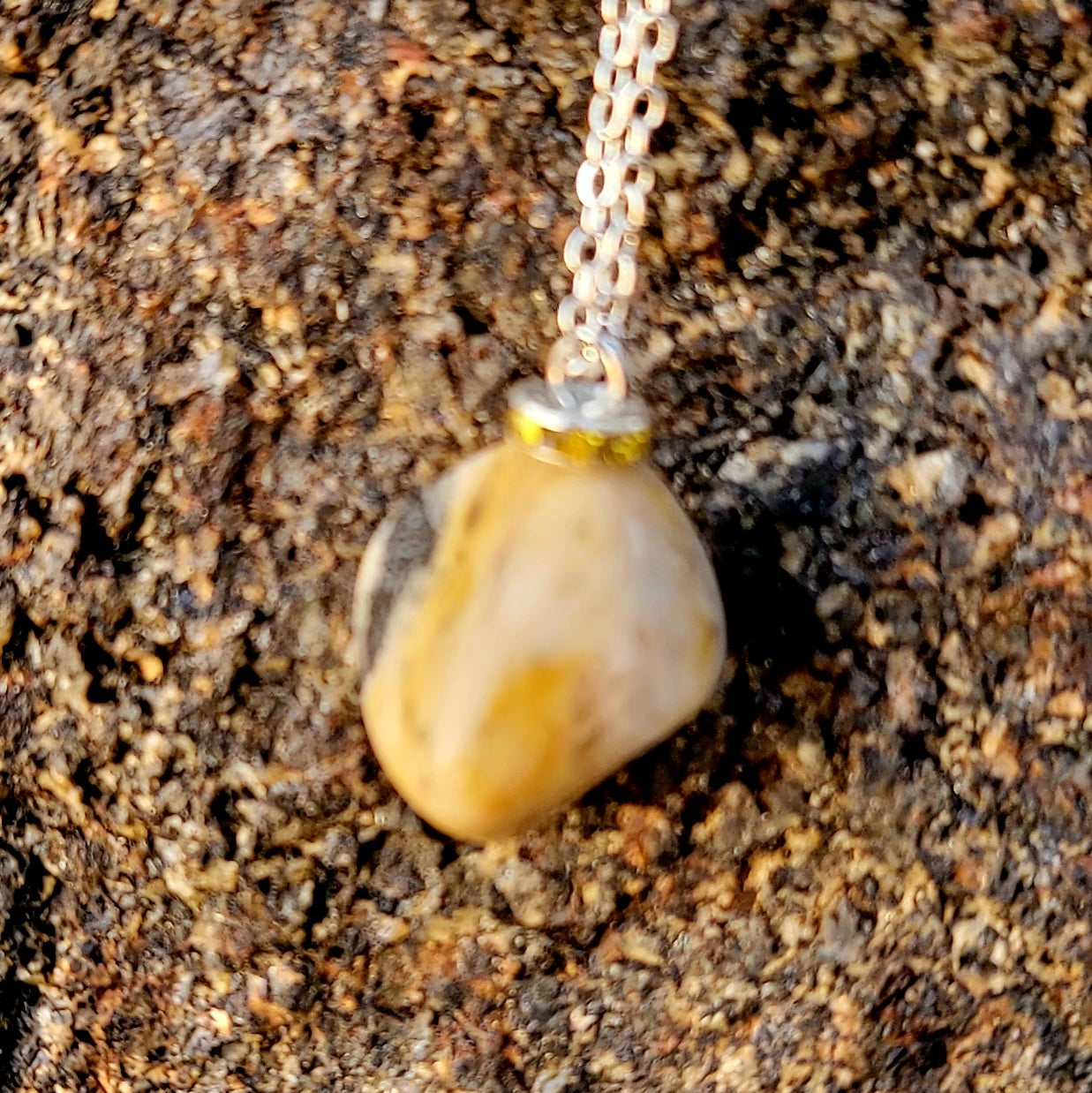 This intricately crafted zebra marble gemstone pendant is a one-of-a-kind masterpiece. Meticulously cut and polished to create an elegant pattern of black, yellow and white striped patterns. This pendant is trimmed with a stainless steel, 20" chain.