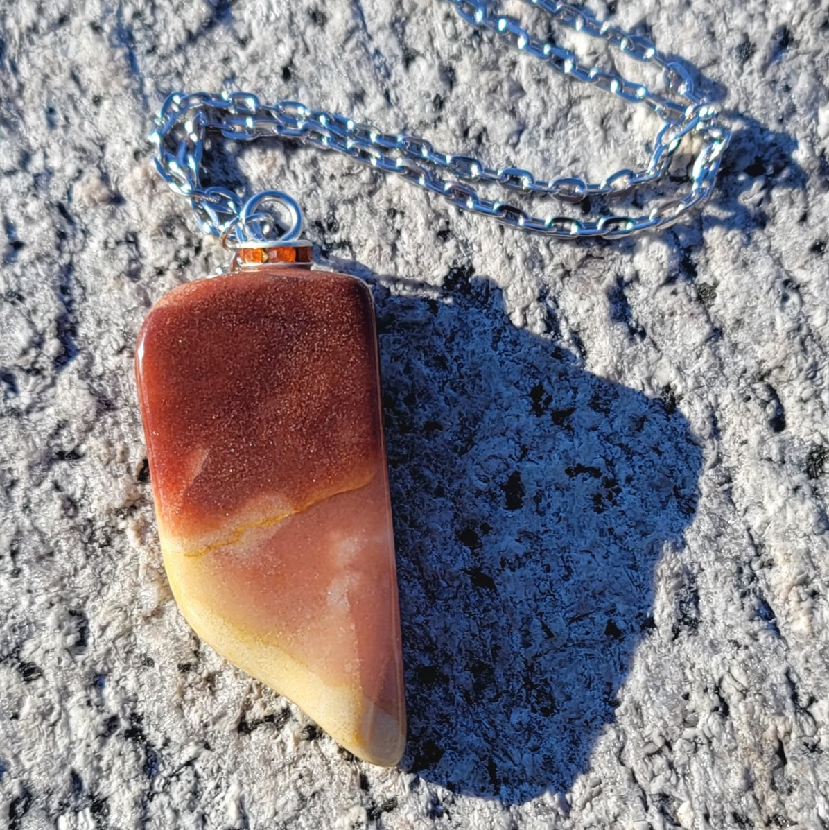 Gorgeous Multi-colored Mookaite Jasper Pendant. This pendant has deep hues of rich colors, such as Reds, Oranges, Browns and Yellow. It is trimmed with a 20" Silver-plated chain. This is a beautiful and very unique piece that is also perfect as a gift