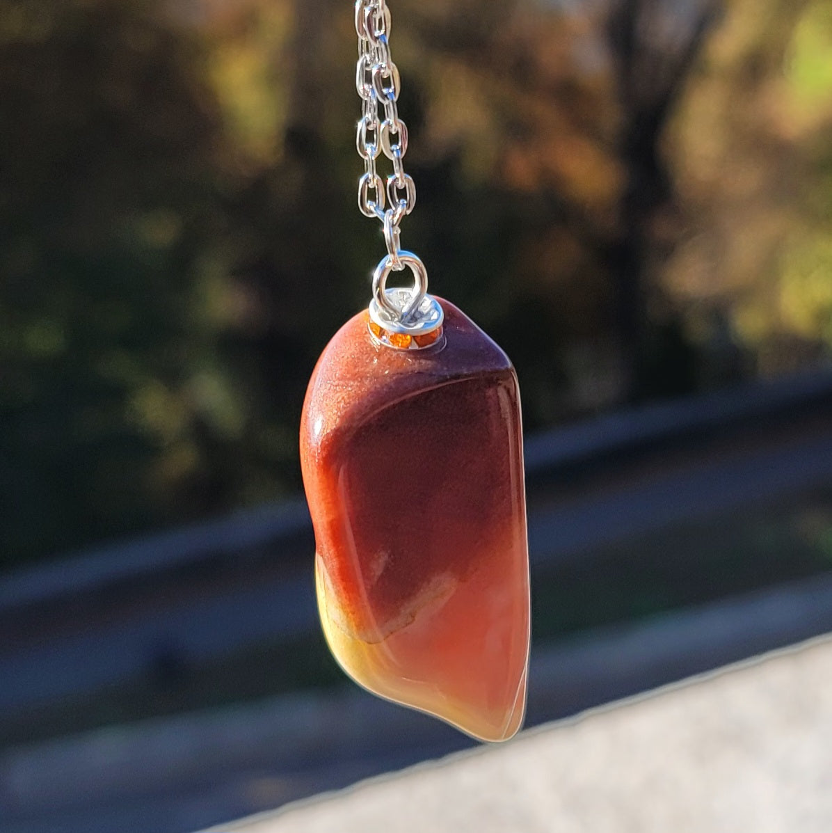 Gorgeous Multi-colored Mookaite Jasper Pendant. This pendant has deep hues of rich colors, such as Reds, Oranges, Browns and Yellow. It is trimmed with a 20" Silver-plated chain. This is a beautiful and very unique piece that is also perfect as a gift