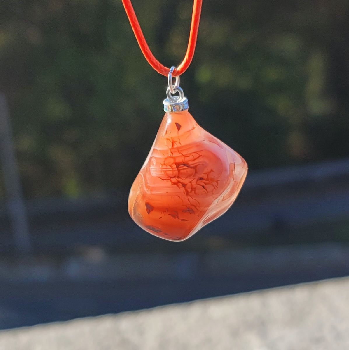 Beautiful Carnelian Agate Pendant with intriguing colors and patterns. It is trimmed with stainless steel findings and an 18" Polyester string.