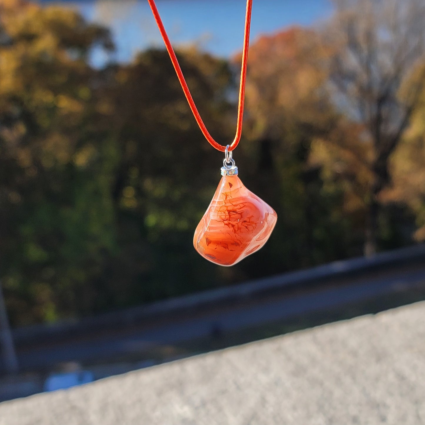 Beautiful Carnelian Agate Pendant with intriguing colors and patterns. It is trimmed with stainless steel findings and an 18" Polyester string.