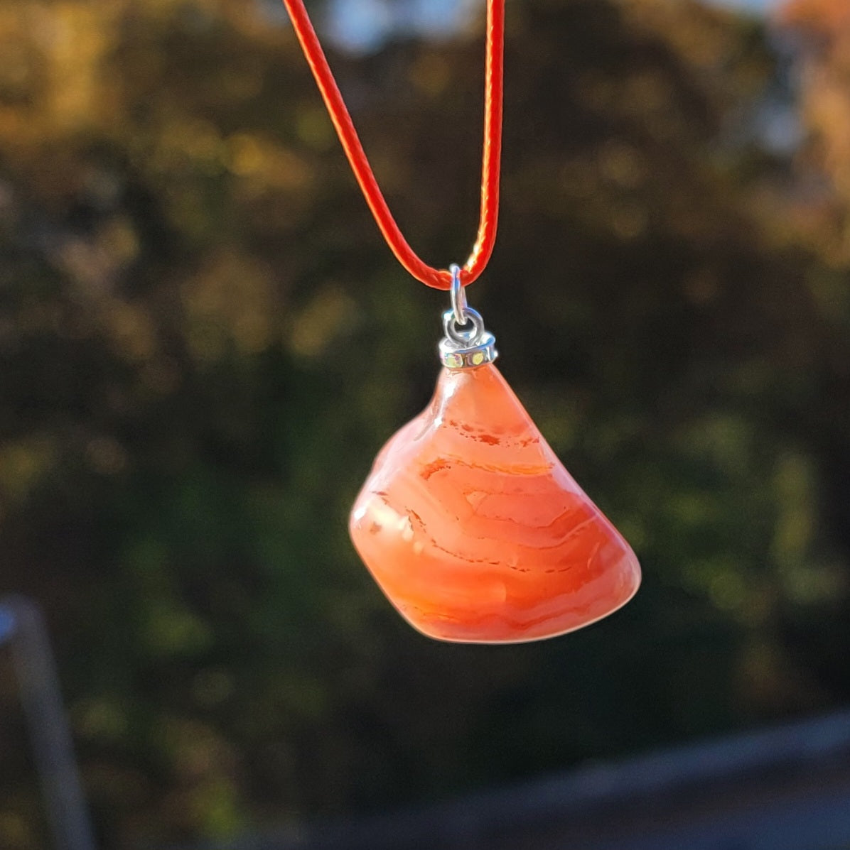 Beautiful Carnelian Agate Pendant with intriguing colors and patterns. It is trimmed with stainless steel findings and an 18" Polyester string.