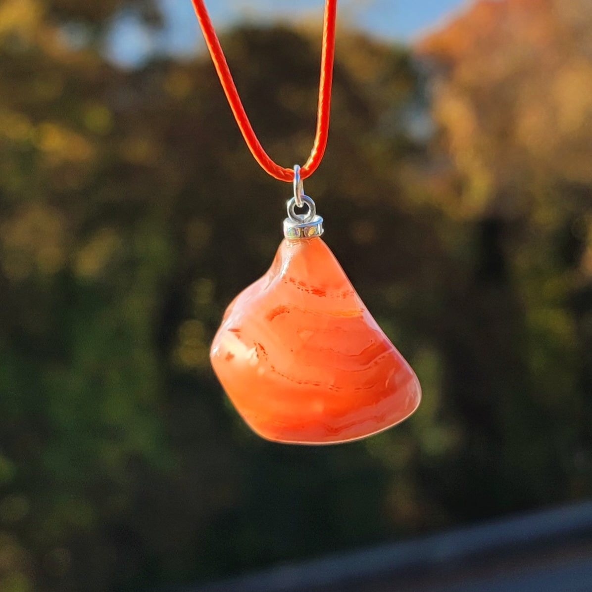 Beautiful Carnelian Agate Pendant with intriguing colors and patterns. It is trimmed with stainless steel findings and an 18" Polyester string.