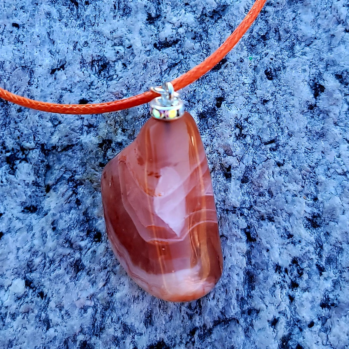 Beautiful Carnelian Agate Pendant with intriguing colors and patterns. It is trimmed with stainless steel findings and an 18" Polyester string.