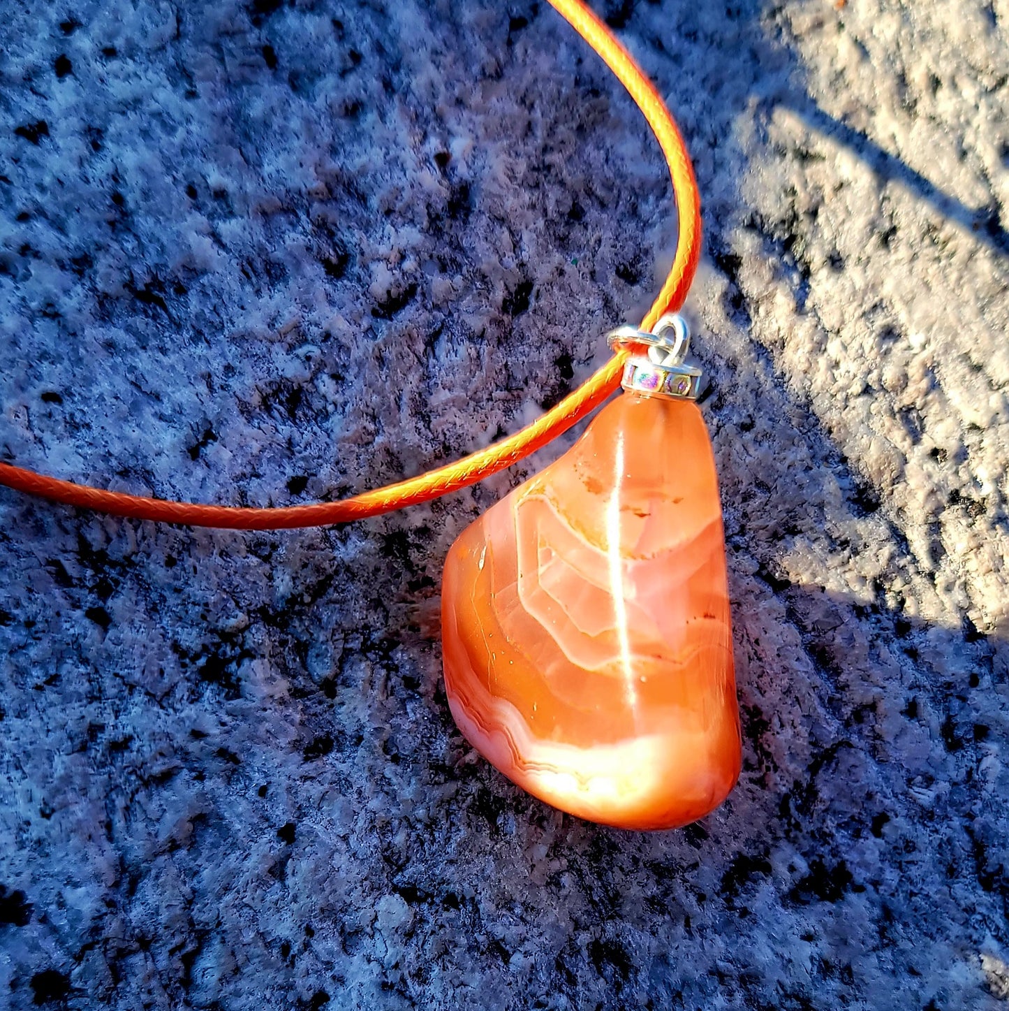 Beautiful Carnelian Agate Pendant with intriguing colors and patterns. It is trimmed with stainless steel findings and an 18" Polyester string.