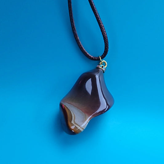 Amazing Desert Jasper Pendant with a very unique shape and an intriguing array of colors. Trimmed with stainless steel findings and a Brown Polyester string.