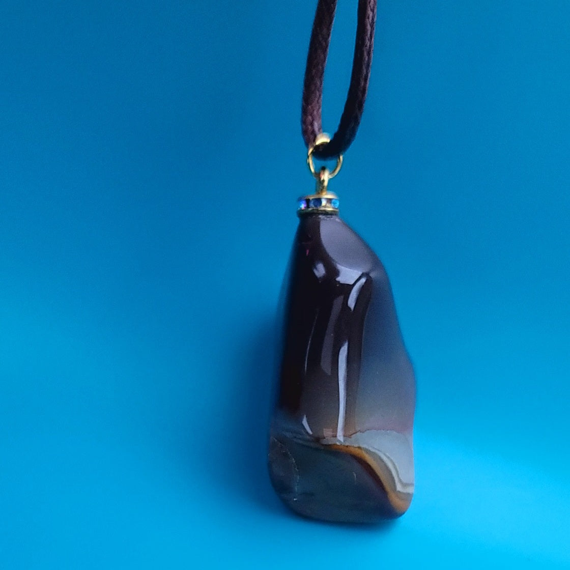 Amazing Desert Jasper Pendant with a very unique shape and an intriguing array of colors. Trimmed with stainless steel findings and a Brown Polyester string.