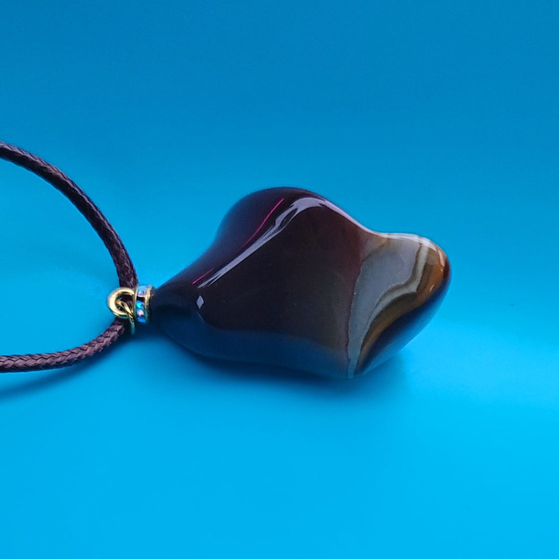 Amazing Desert Jasper Pendant with a very unique shape and an intriguing array of colors. Trimmed with stainless steel findings and a Brown Polyester string.