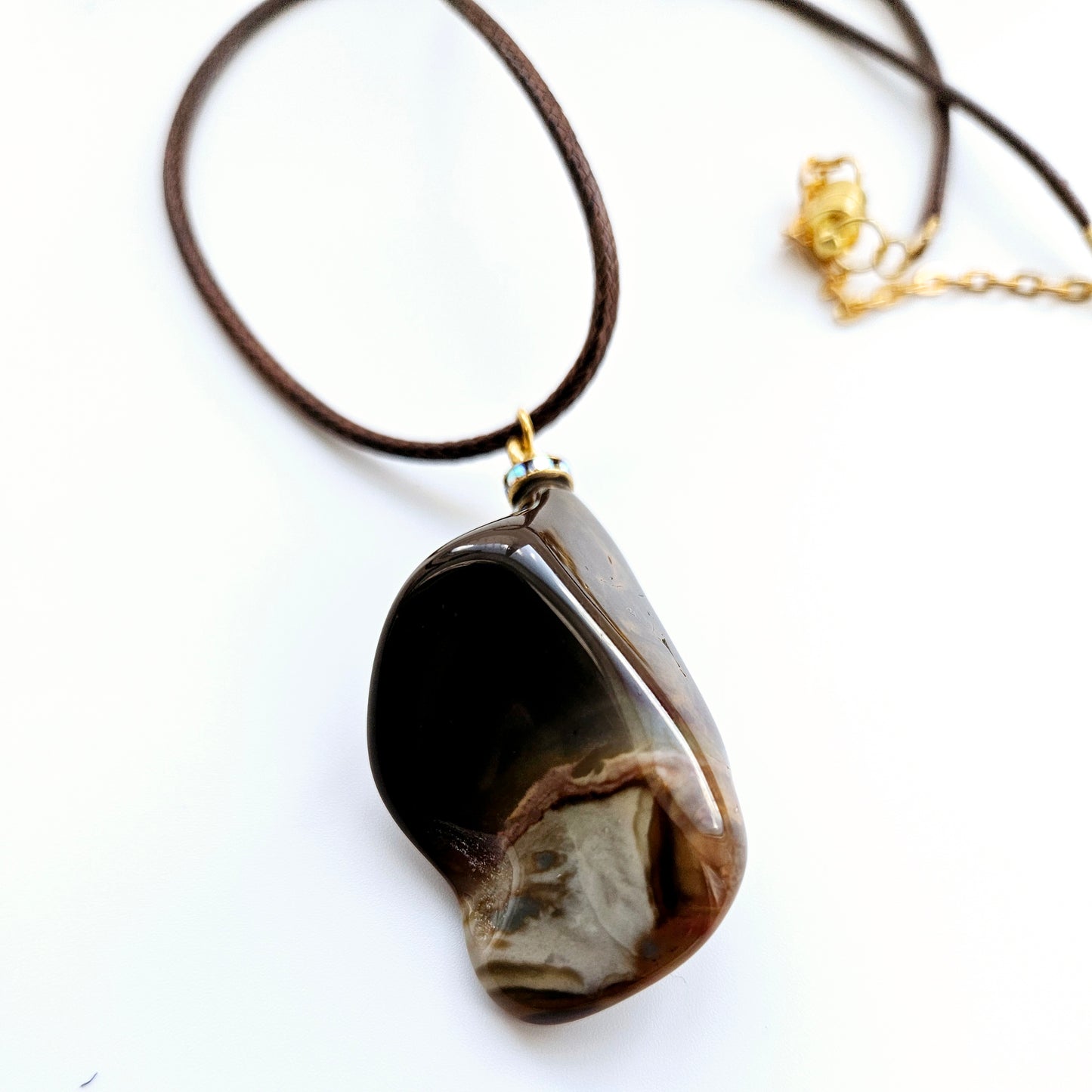 Amazing Desert Jasper Pendant with a very unique shape and an intriguing array of colors. Trimmed with stainless steel findings and a Brown Polyester string.