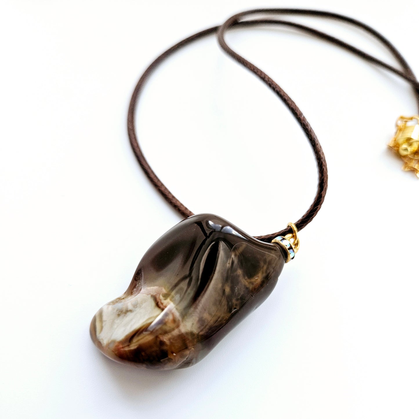 Amazing Desert Jasper Pendant with a very unique shape and an intriguing array of colors. Trimmed with stainless steel findings and a Brown Polyester string.