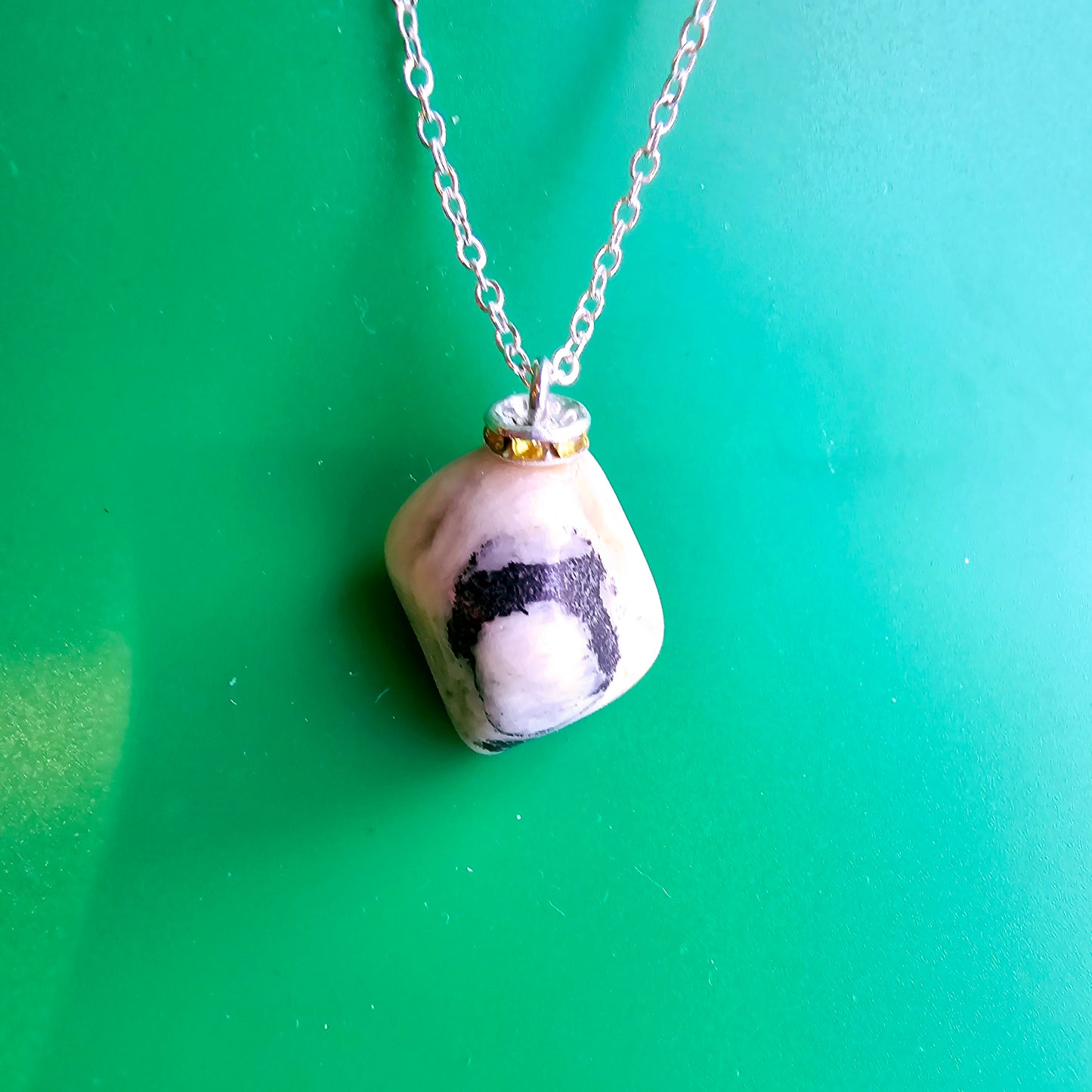 This intricately crafted zebra marble gemstone pendant is a one-of-a-kind masterpiece. Meticulously cut and polished to create an elegant pattern of black, yellow and white striped patterns. This pendant is trimmed with a stainless steel, 20" chain.