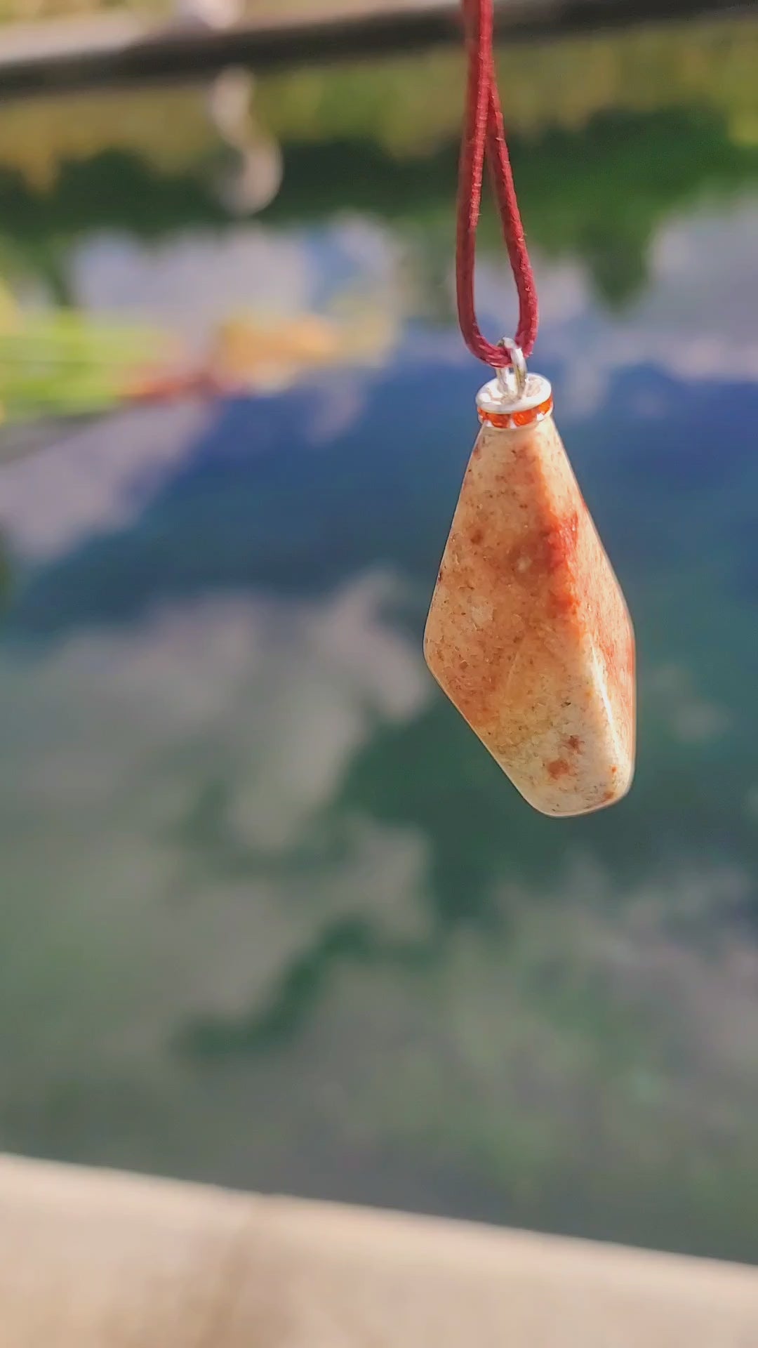 Very unique and powerful sunstone pendant. This stone has an intriguing color pattern consisting of Reds, Oranges, Green and Brown. It also has a unique shape that will definitely stand out. This is a true one-of-a-kind piece. Pictured in video, hanging.