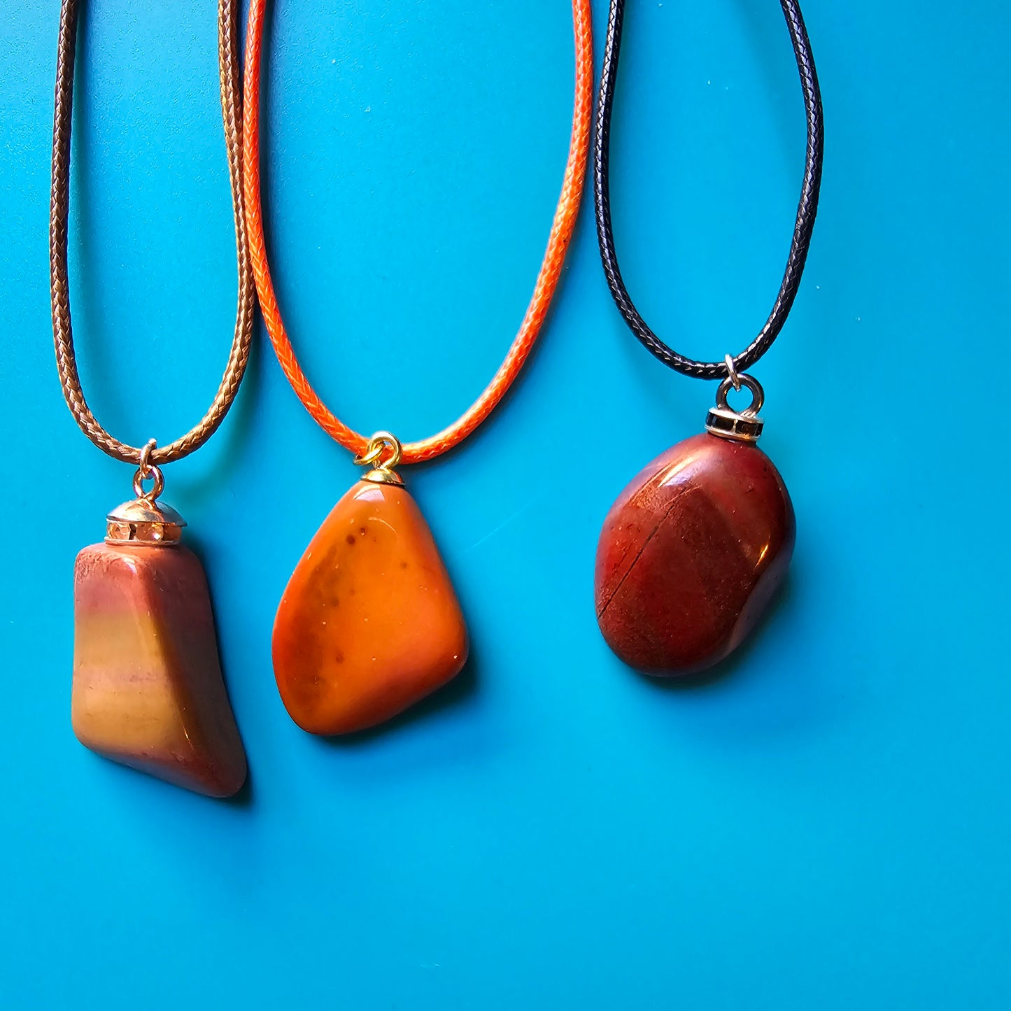 Beautiful and intricate Red Jasper Pendant. Finished with Black and Silver trim and an 18" Polyester string. Pictured with two other Jasper Pendants.