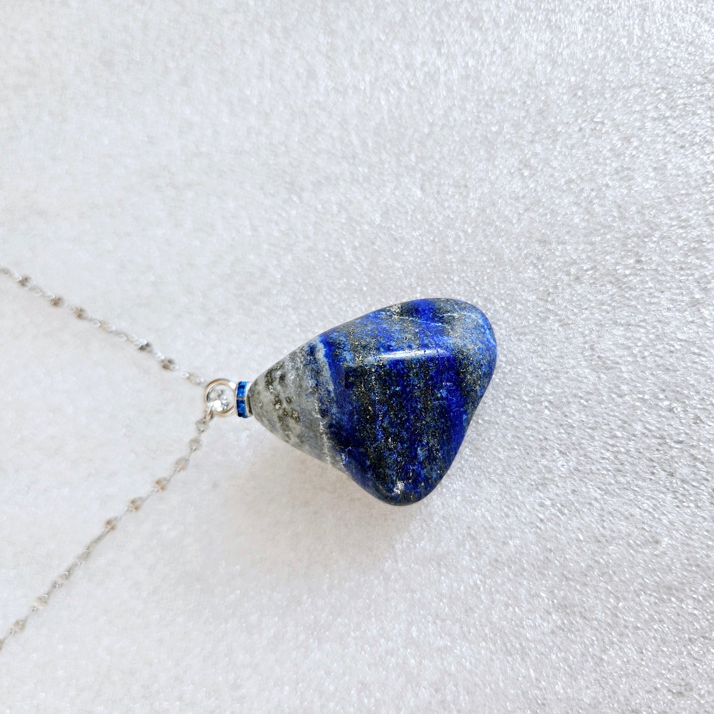 Striking Lapis Lazuli Pendant with deep hues of Blue and Greys. It is trimmed with Silver-Plated findings and a 20" sterling Silver chain.