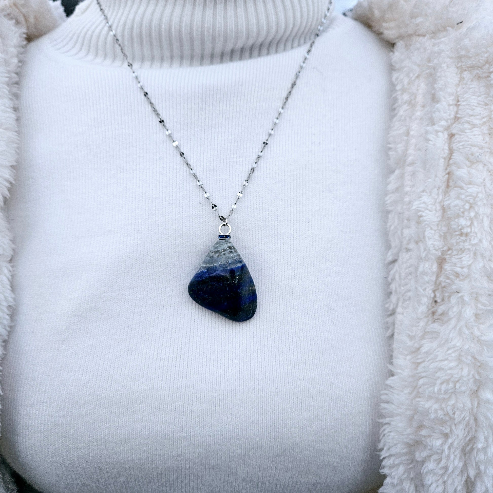 Striking Lapis Lazuli Pendant with deep hues of Blue and Greys. It is trimmed with Silver-Plated findings and a 20" sterling Silver chain.