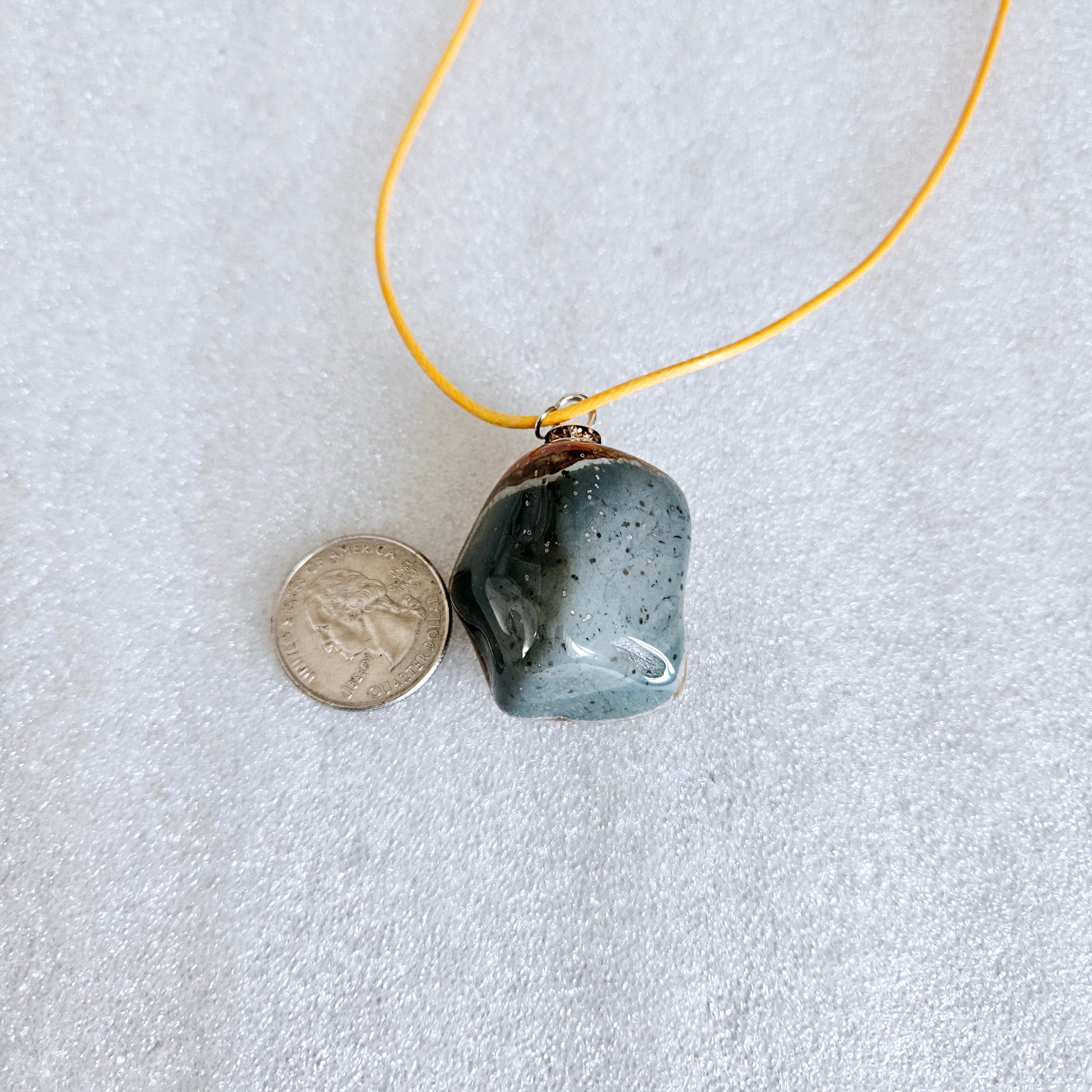 Unique and bold Desert Jasper Pendant with a very intricate color pattern. You will be amazed by its stunning beauty. It is finished with a Yellow Polyester string. Pictured with a quarter for size reference.