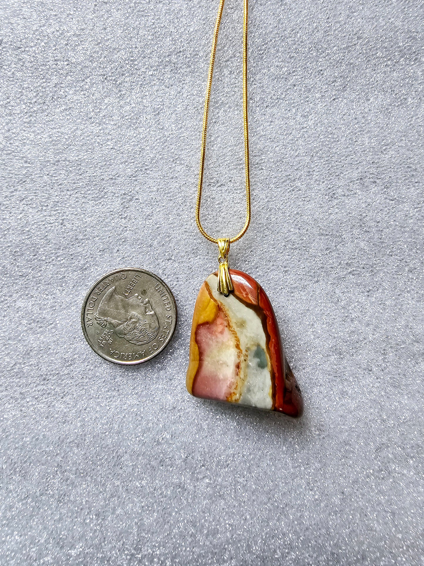 A stunning beauty of our Desert Jasper Pendant. This unique stone features a mesmerizing color pattern and is known for its powerful metaphysical properties. It promotes inner peace, balance and protection while enhancing creativity and self-expression. Front side shown with US Quarter.