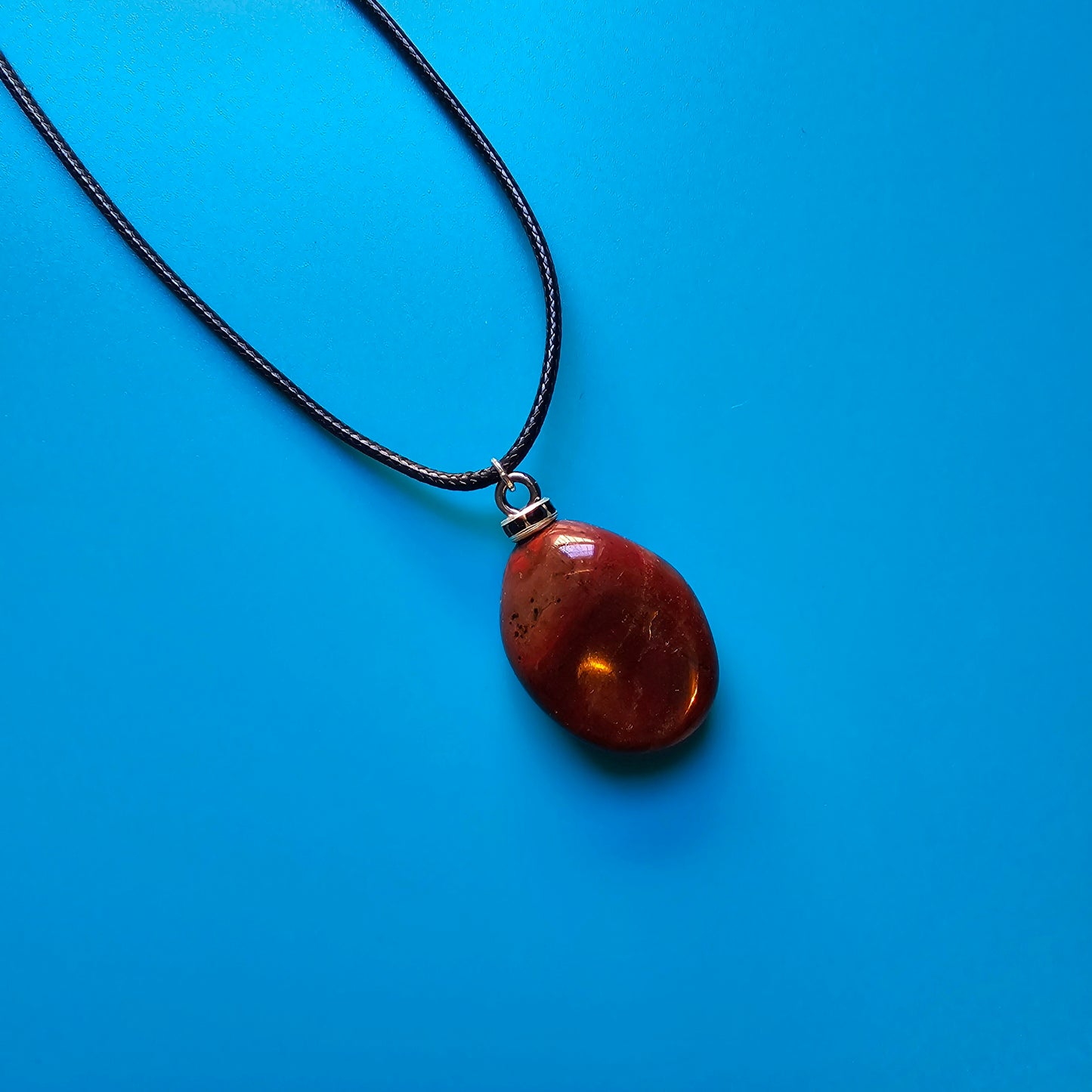 Beautiful and intricate Red Jasper Pendant. Finished with Black and Silver trim and an 18" Polyester string.