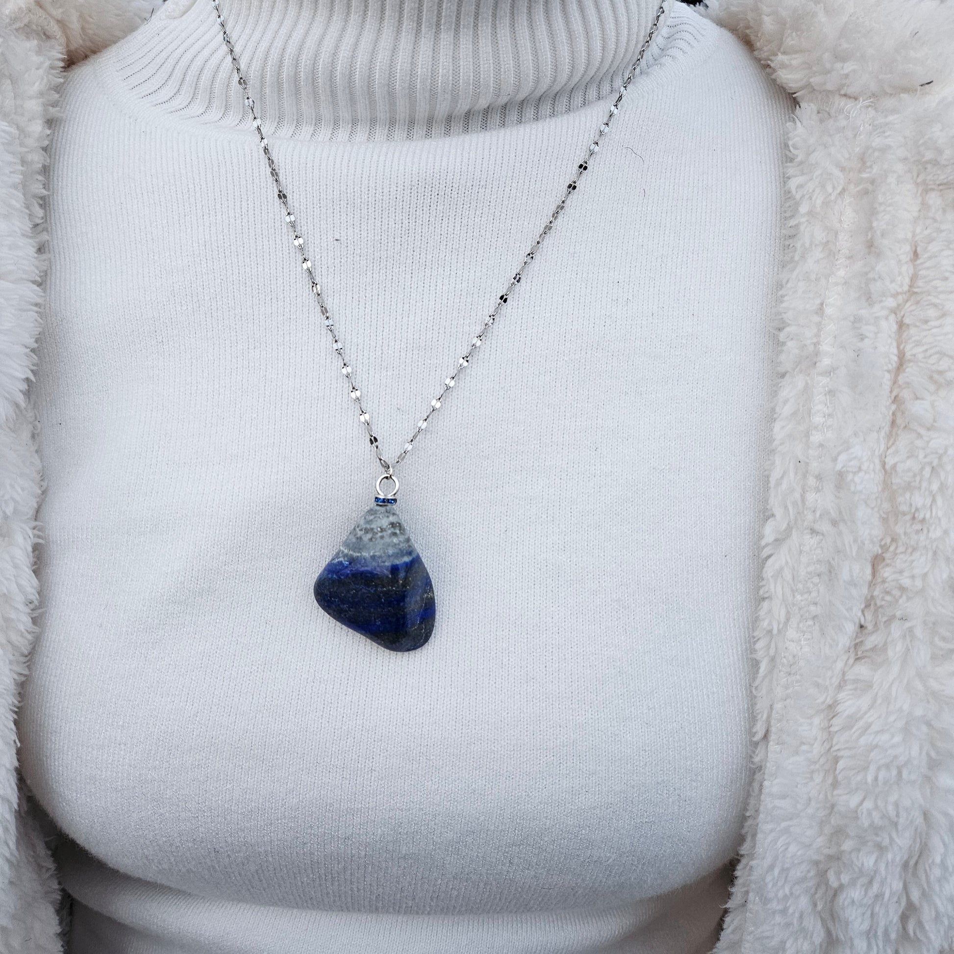 Striking Lapis Lazuli Pendant with deep hues of Blue and Greys. It is trimmed with Silver-Plated findings and a 20" sterling Silver chain.