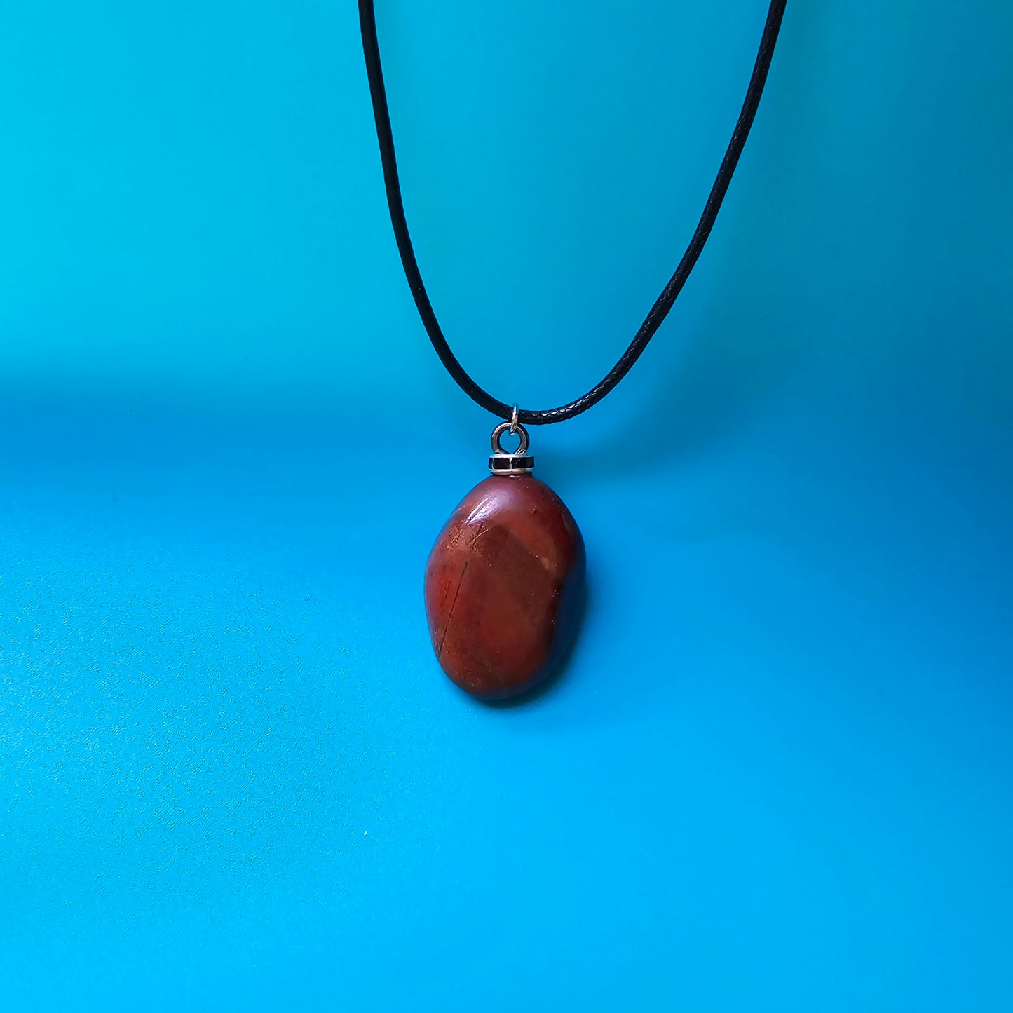 Beautiful and intricate Red Jasper Pendant. Finished with Black and Silver trim and an 18" Polyester string.