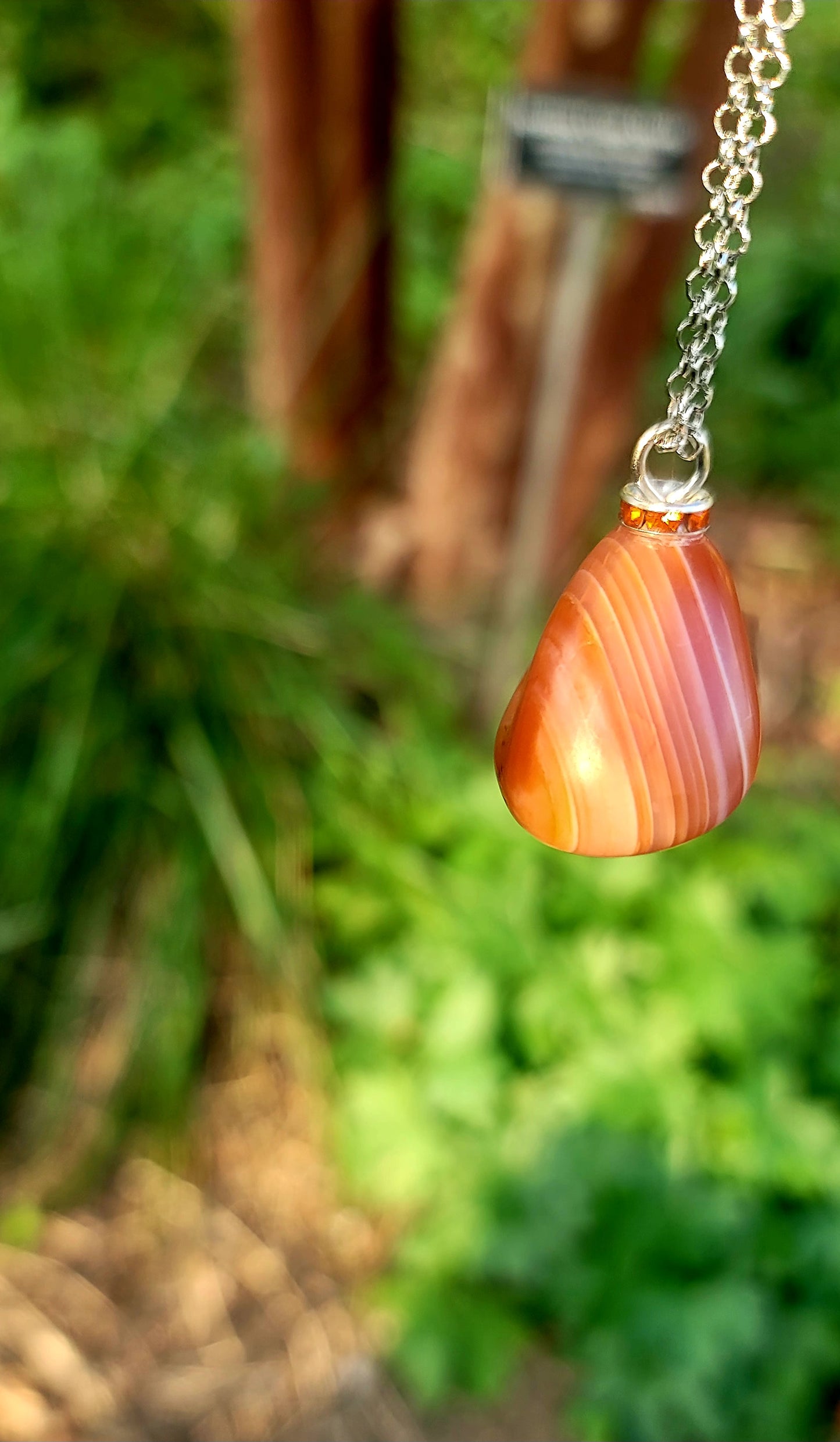 Beautiful Orange-red carnelian pendant with stunning bands running around it. Be intrigued by its pattern and vibrant colors.