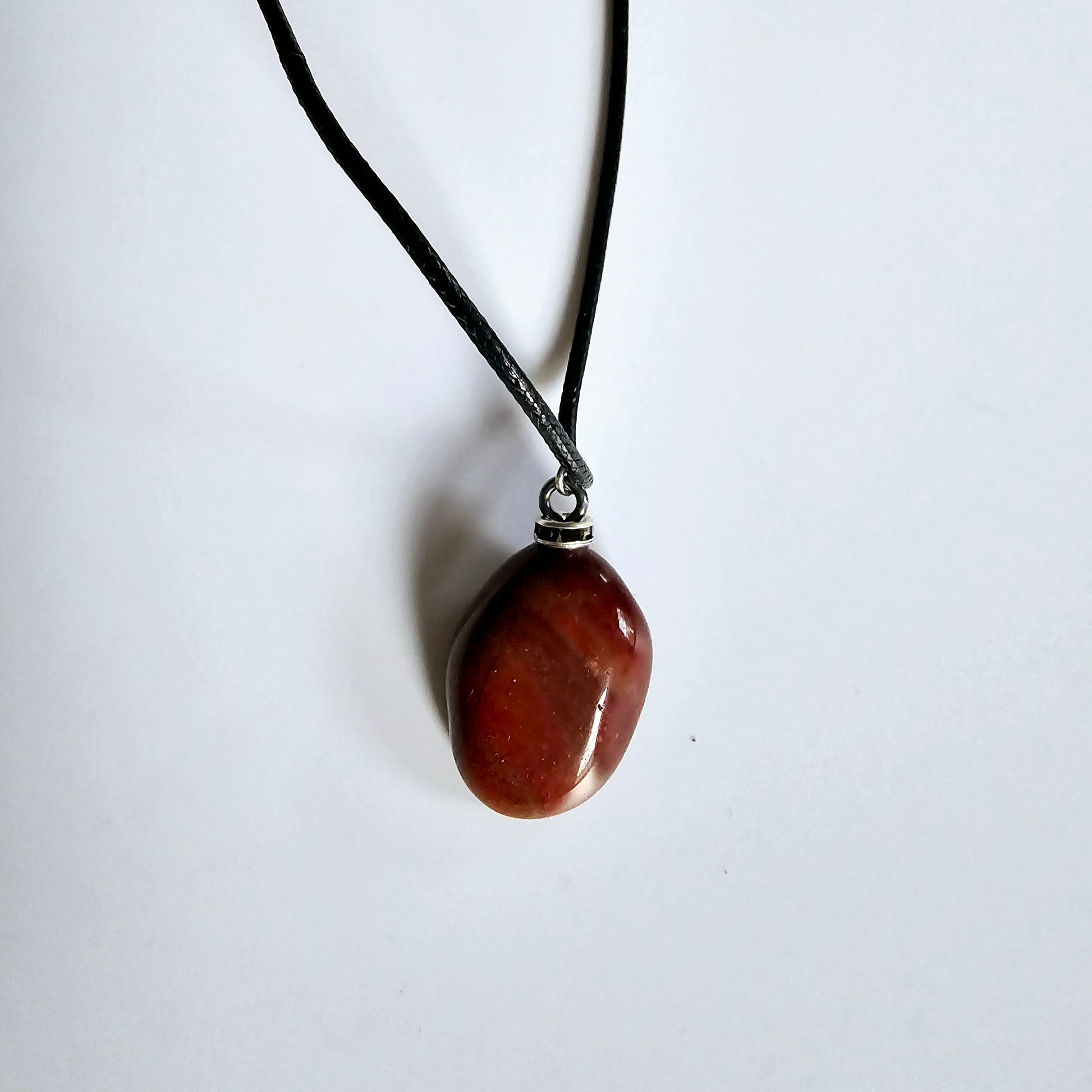 Beautiful and intricate Red Jasper Pendant. Finished with Black and Silver trim and an 18" Polyester string.