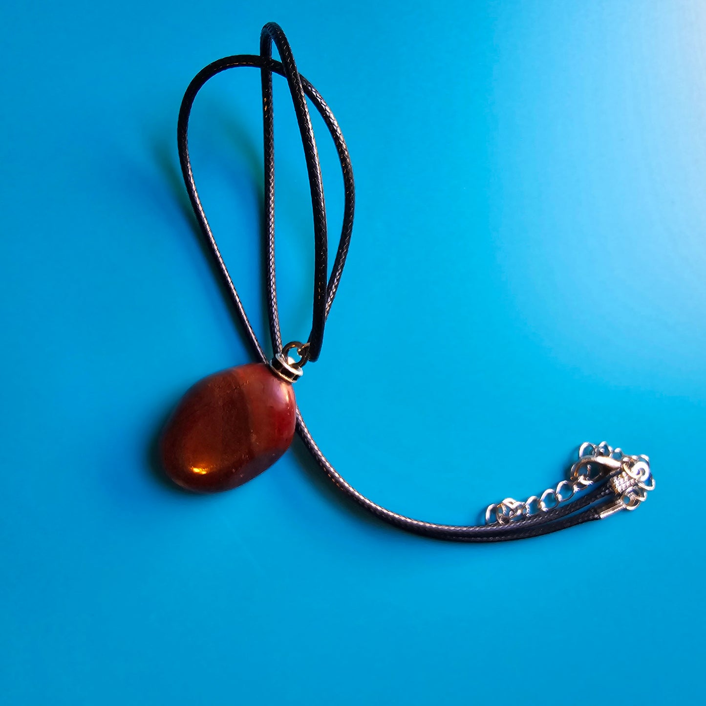 Beautiful and intricate Red Jasper Pendant. Finished with Black and Silver trim and an 18" Polyester string.