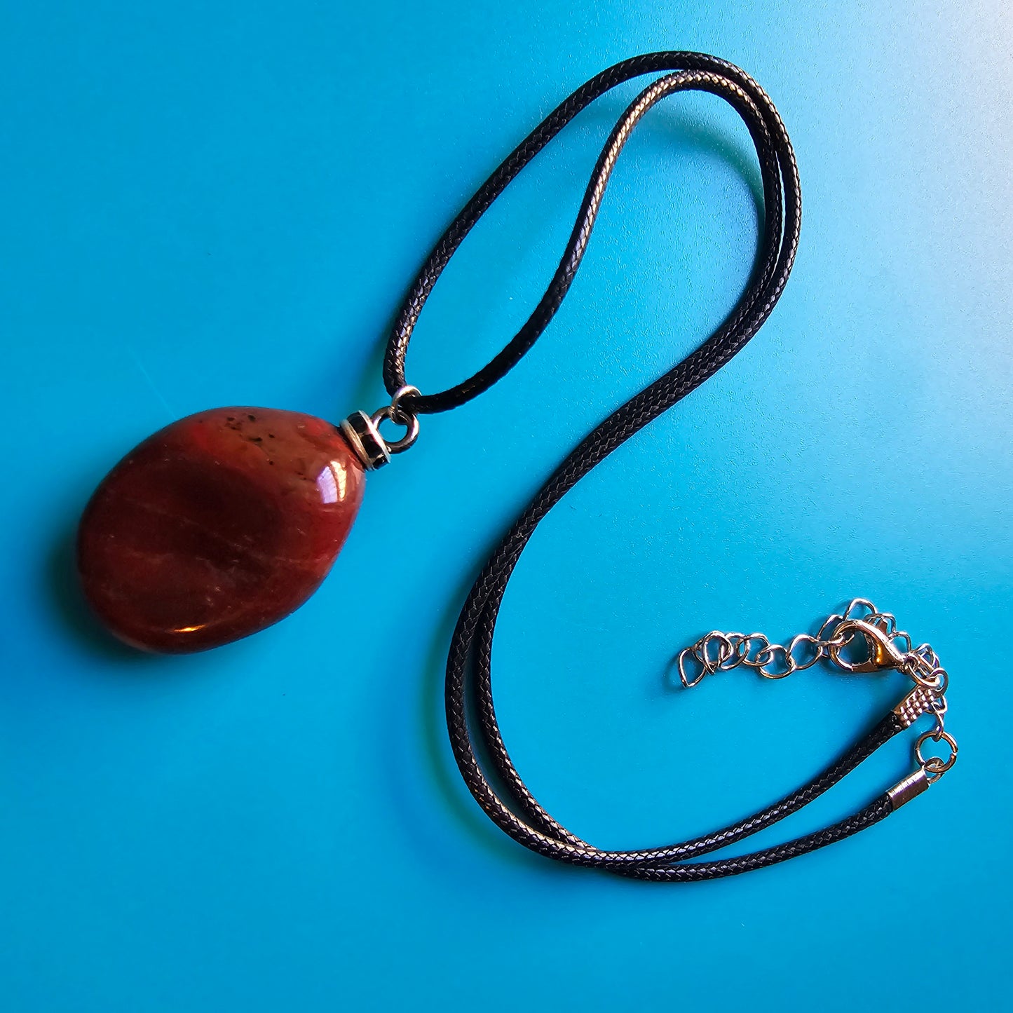 Beautiful and intricate Red Jasper Pendant. Finished with Black and Silver trim and an 18" Polyester string.