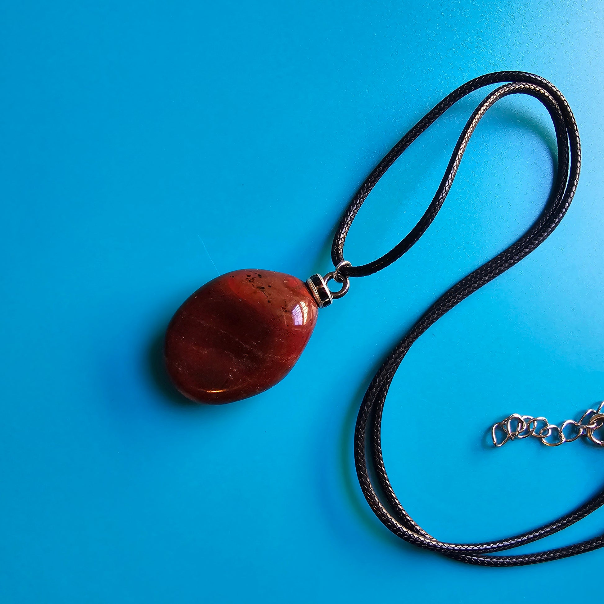 Beautiful and intricate Red Jasper Pendant. Finished with Black and Silver trim and an 18" Polyester string.