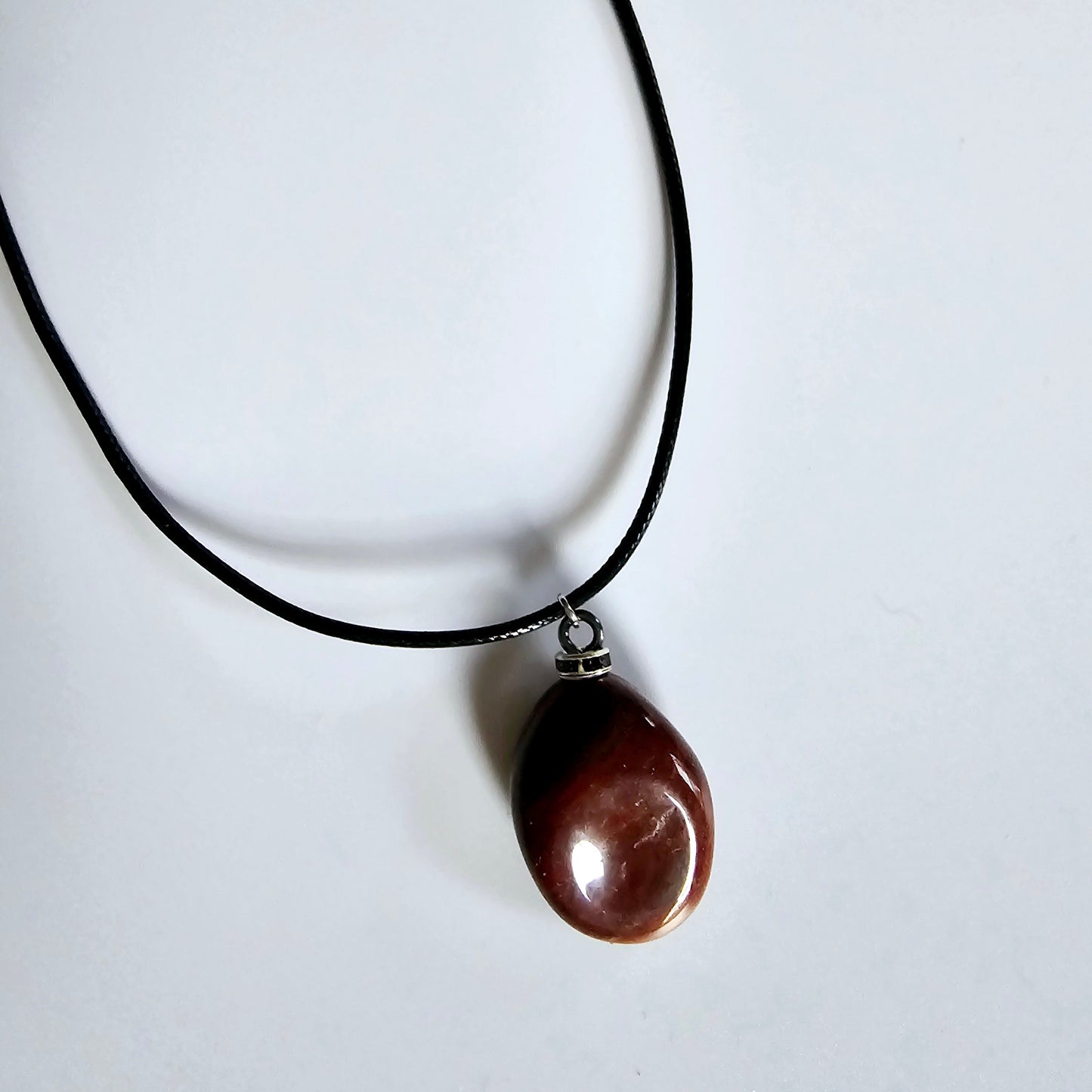 Beautiful and intricate Red Jasper Pendant. Finished with Black and Silver trim and an 18" Polyester string.