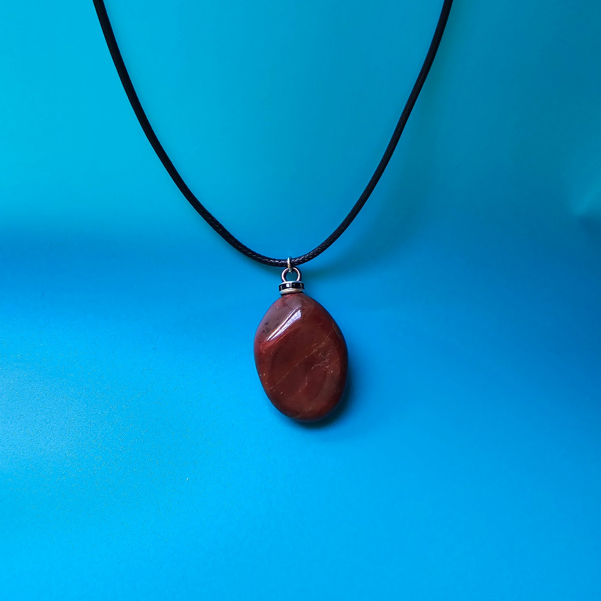 Beautiful and intricate Red Jasper Pendant. Finished with Black and Silver trim and an 18" Polyester string.