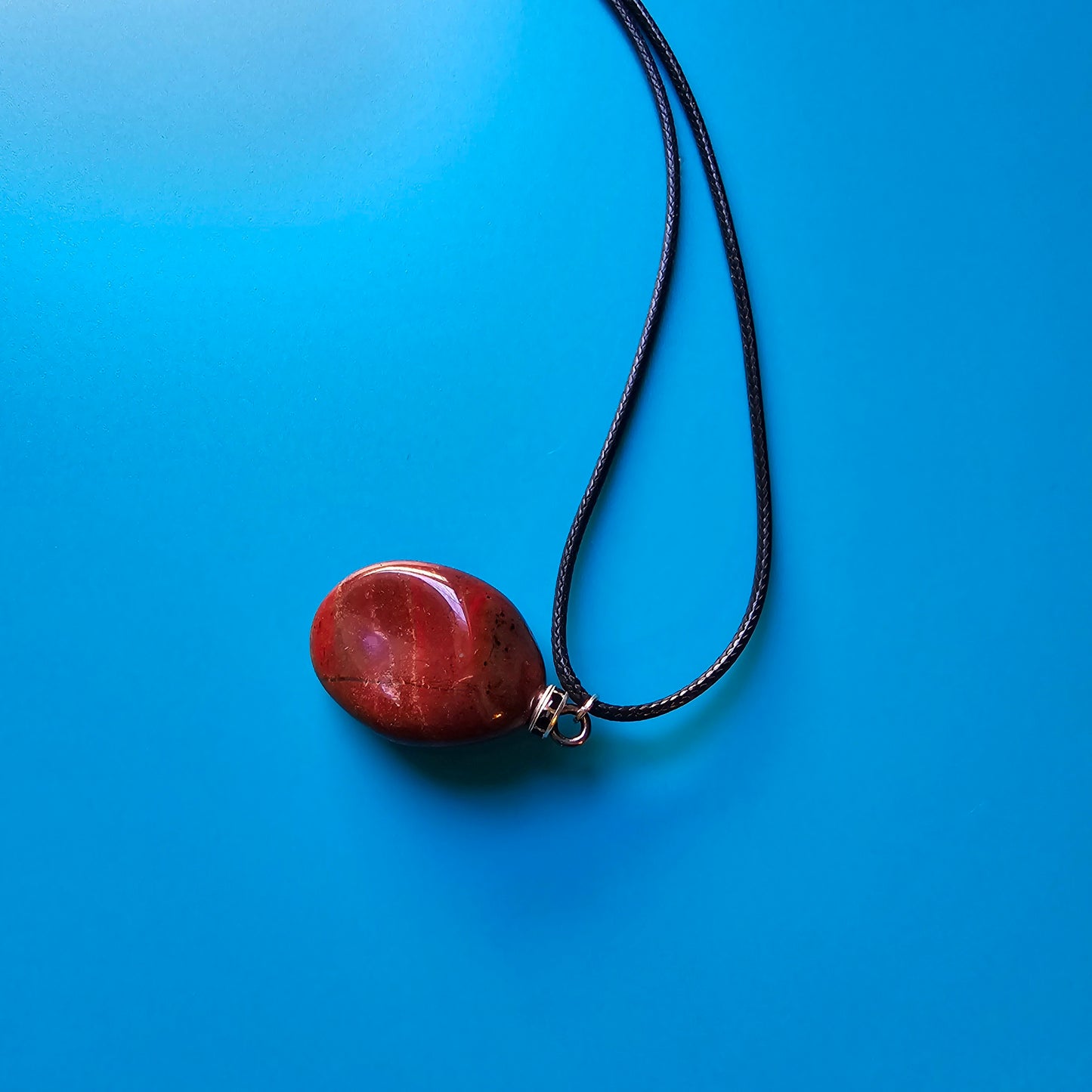 Beautiful and intricate Red Jasper Pendant. Finished with Black and Silver trim and an 18" Polyester string.