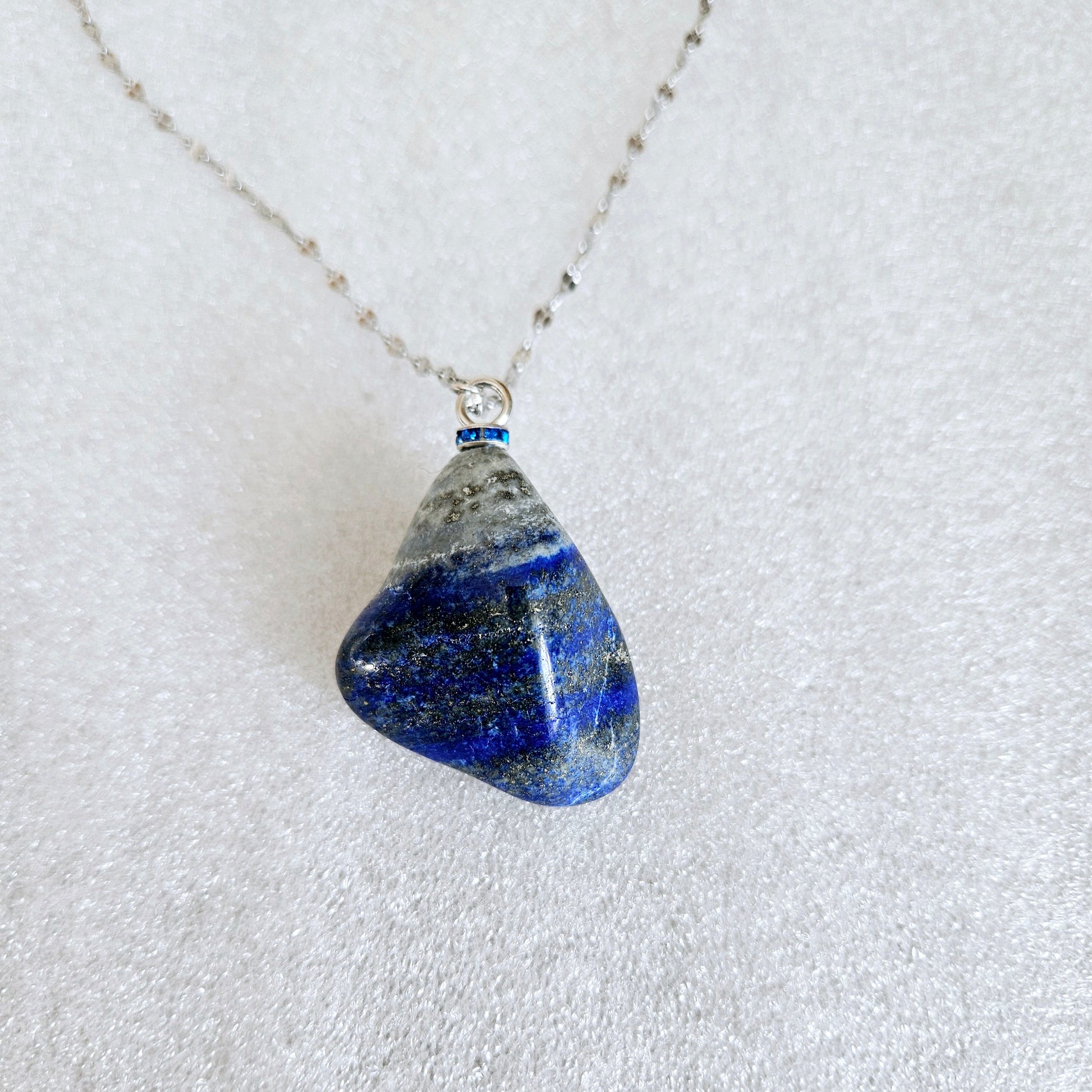 Striking Lapis Lazuli Pendant with deep hues of Blue and Greys. It is trimmed with Silver-Plated findings and a 20" sterling Silver chain.